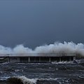 Kołobrzeskie molo zalewane przez sztormowe fale na Bałtyku
