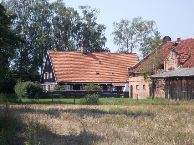 Drewnica-zabytkowy dom podcieniowy z czerwonymi okiennicami.